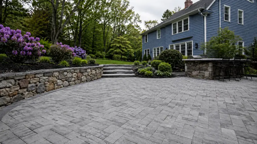 Completed stone paver patio with retaining wall, granite steps and landscaping in Johnston, Rhode Island — Reyes Landscaping